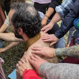 Rev. Prakasa kneels to deliver a blessing to the Naropa M. Div cohort